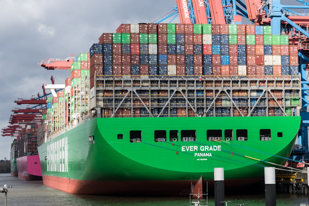 services-02 Huge container ship docked at Hamburg terminal in bright daylight.